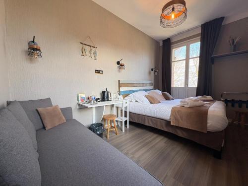 a bedroom with two beds and a couch and a table at Logis Hôtel- Restaurant Le Relais Guillaume de Normandy-PARKING GRATUIT--VUE BAIE TERRASSE-CALME-BORNES ELECTRIQUE-LOCAL VELOS SÉCURISÉ in Saint-Valéry-sur-Somme