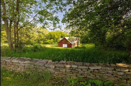 a stone wall in front of a red barn at Oak & Anchor Inn in Penn Yan
