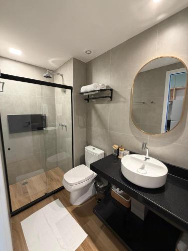 a bathroom with a toilet and a sink and a mirror at Flat Premium Muro Alto-conforto a 150m do mar in Ipojuca