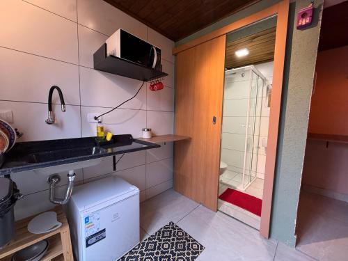 a small kitchen with a sink and a shower at Vilarejo hospedagem- Espaço Beco Carioca in Ilha do Mel