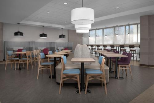 a dining room with tables and chairs in a cafeteria at Home2 Suites by Hilton Arundel Mills BWI Airport in Hanover