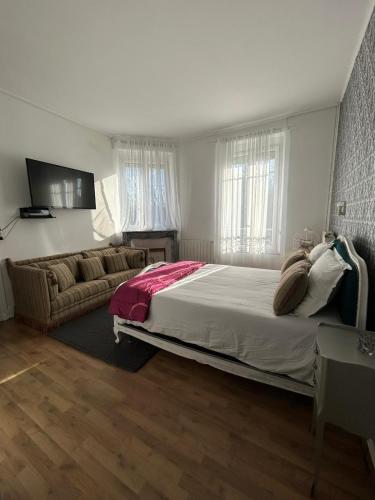 a bedroom with a large bed and a couch at Maison Charmante in Vervins