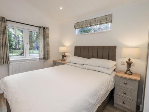 a bedroom with a white bed and two windows at Lakeside Lodge in Preston