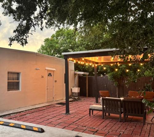 a patio with two benches and a pergola with lights at Cozy Private House near Miami Airport - Free parking - 01 in Miami