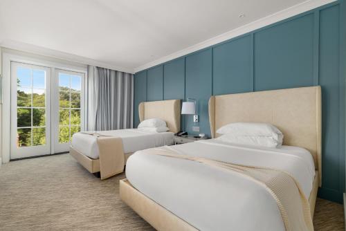 two beds in a room with blue walls at The Shepherd Hotel Downtown Clemson in Clemson