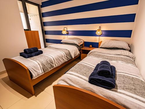 two beds in a room with blue and white stripes at Cobalt Canopy a Spacious 2 Bedroom Apartment in St. Paul's Bay