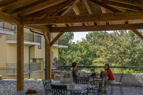 two people sitting at tables under a wooden pergola at B&B Le Ginestre in Viggianello