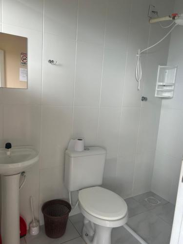 a white bathroom with a toilet and a sink at Pousada Mar & Sol in Torres