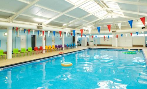 a large swimming pool in a gym with colorful chairs at Boquhanran Caravan, Whitley Bay in Hartley