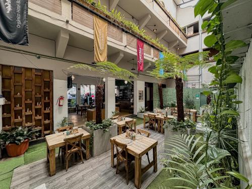 a restaurant with wooden tables and potted plants at FRONTERA 49 Roma Norte Hostal in Mexico City