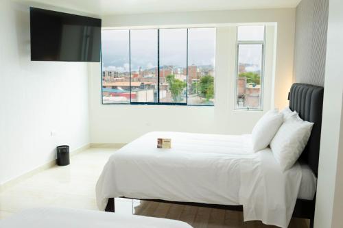 a white bedroom with a large bed and a window at Solay Inn in Ayacucho
