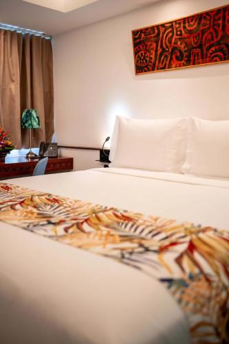 a bedroom with a bed and a table with a lamp at Maitai Express Tahiti in Papeete