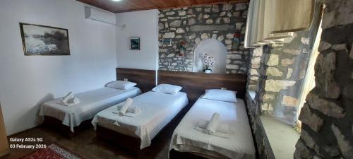 a room with two beds and a stone wall at Veranda Guest House in Berat