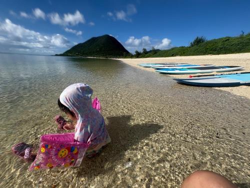 a child sitting in a chair on the beach at Kukaru クカル 伊平屋島の古民家一棟貸し in Gakiya
