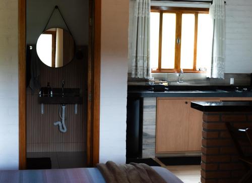a bathroom with a sink and a mirror in a room at Chalé Recanto da Paciência in Camanducaia