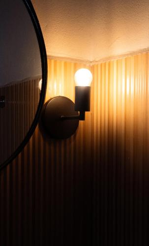 a light attached to a wall with a mirror at Chalé Recanto da Paciência in Camanducaia