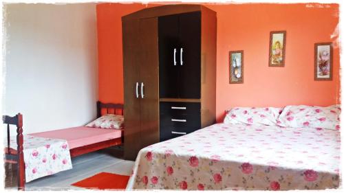 a bedroom with two beds and a cabinet at Apt. de Setiba - HOSPEDARIA OCA RUCA in Guarapari