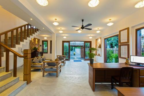 a living room with a ceiling fan and a desk at Vina Beach Pool Villas in Hoi An