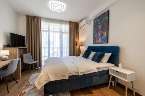 a bedroom with a large blue bed and a desk at inJoy in Sajmište