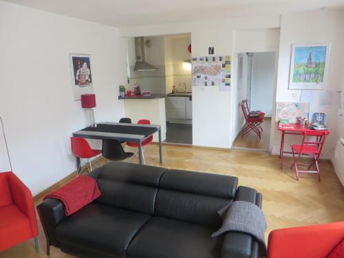 ein Wohnzimmer mit einem schwarzen Sofa und einem Tisch in der Unterkunft Au Quai Des Pecheurs in Straßburg
