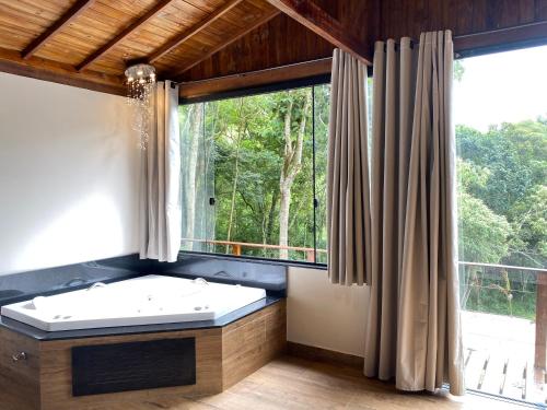 a bathroom with a tub and a large window at Cabana Dream Garden in Nova Friburgo