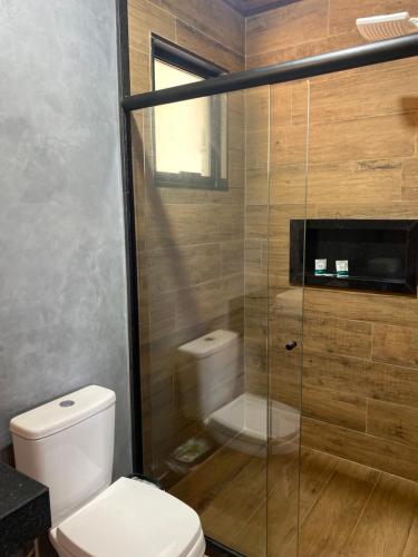 a bathroom with a toilet and a glass shower at Cabana Dream Garden in Nova Friburgo