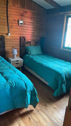 two beds in a room with wooden walls at Atardecer Inolvidable in Tomé