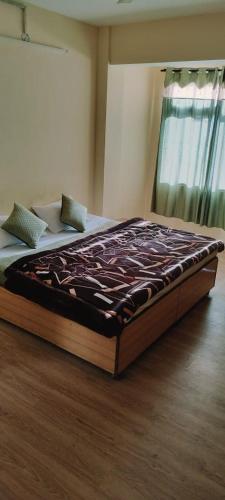 a large bed sitting on a wooden floor in a bedroom at Hotel Vamika in Manāli