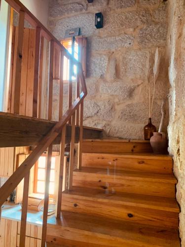 a wooden staircase in a room with a stone wall at Refúgio da Póvoa Dão in Silgueiros