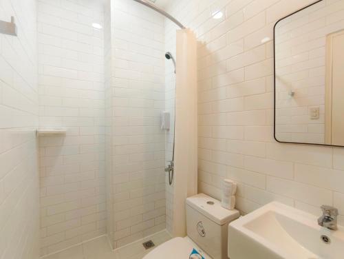 a white bathroom with a toilet and a sink at Voss Condominium in Manila