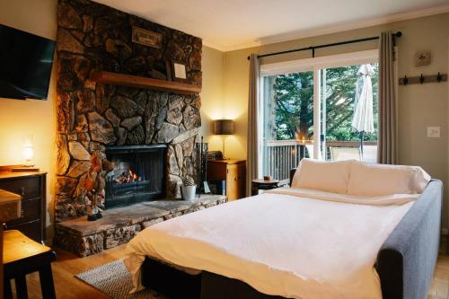 a bedroom with a bed and a stone fireplace at Peaceful Mountain Sanctuary near Arrowhead Village in Lake Arrowhead