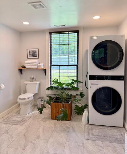 a bathroom with a washing machine and a toilet at Couples Cottage with Hot Tub in Mathews