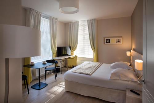 a bedroom with a bed and a desk with a computer at Domitys - Le Carillon d'or in Maubeuge