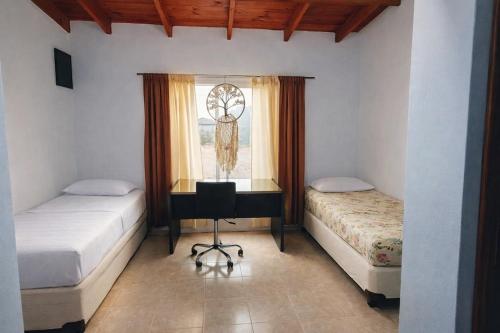 a bedroom with two beds and a desk and a window at Casa de campo in Puerto Madryn
