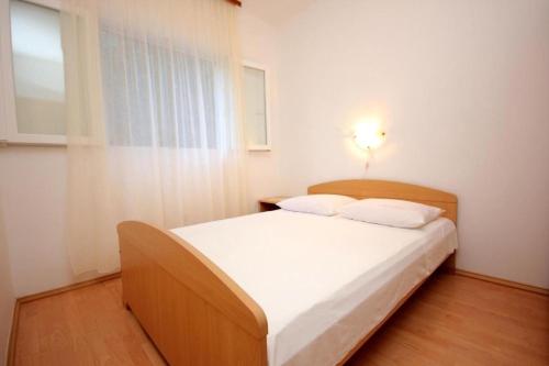 a bedroom with a bed with white sheets and a window at House Paulo3 in Rogačić