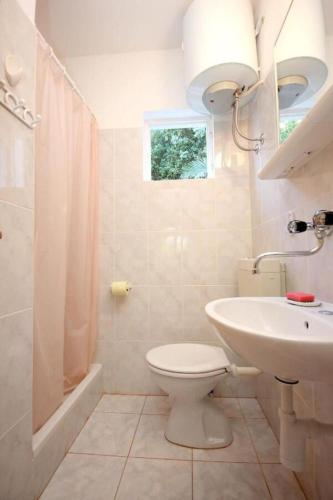 a white bathroom with a toilet and a sink at House Paulo3 in Rogačić