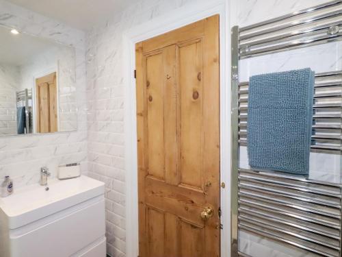 a bathroom with a sink and a wooden door at Riverside Cottage in Warkworth