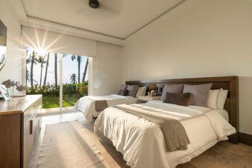 a bedroom with two beds and a large window at Exclusive Oceanfront Apartment Beach access in Acapulco
