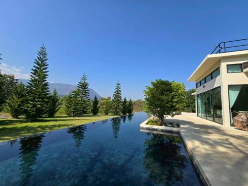 a house with a pond in front of it at Sa Prung on the mountain - สะพรั่งกลางขุนเขา in Ban Tham