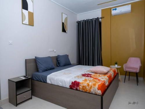 een slaapkamer met een bed en een roze stoel bij Maison Recla in Lomé