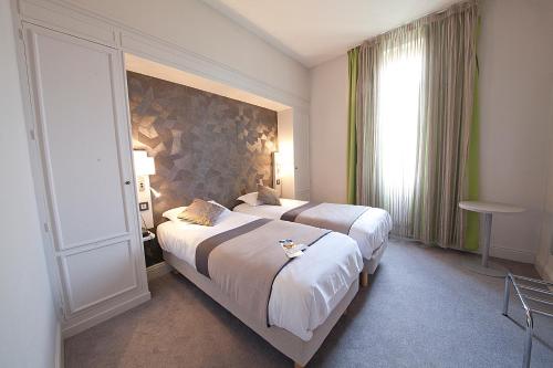 a hotel room with two beds and a window at Hôtel Albert Elisabeth Gare SNCF in Clermont-Ferrand