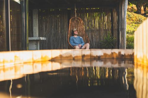 a man sitting in a swing next to a body of water at Cabañas Mirador de Matanzas in Matanzas