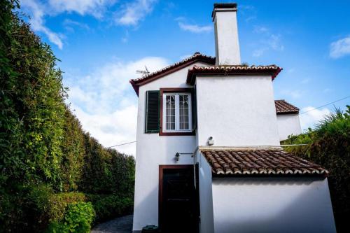 a small white house with a chimney and a door at O Moinho (Furnas Hot Springs) in Furnas