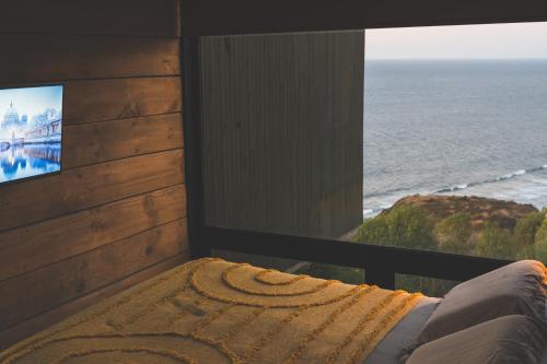 a room with a bed and a tv and the ocean at Cabañas Mirador de Matanzas in Matanzas