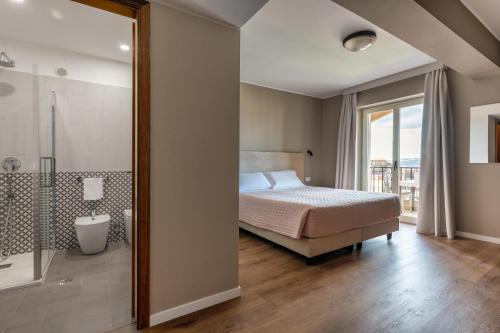 una camera da letto con un letto e un bagno con una doccia di Hotel Pomara a San Michele di Ganzaria