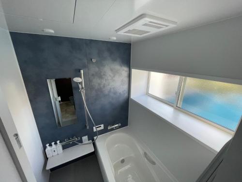 a bathroom with a white tub and a window at ゲストハウスKe'oKe'o in Higashikagawa