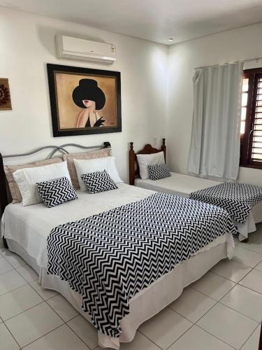 a bedroom with two beds and a painting on the wall at Espaço Ybirá in Marechal Deodoro