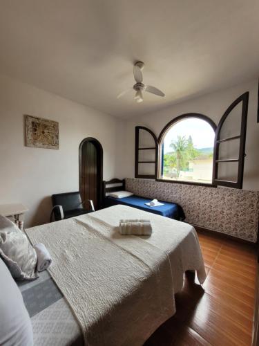 a bedroom with a bed and a large window at Casa da Edna in Guarujá