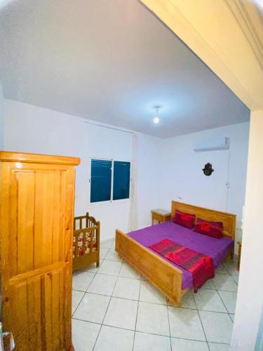 a bedroom with a bed in a white room at V résidence in Ḩamādat al Kebalou