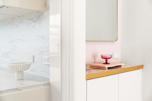 a white bathroom with a red bowl on a counter at Belle Escapes - The Light House in Glenelg